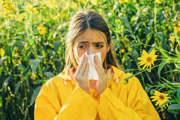 Csicsóka virágzik. Szalvéta orrfolyáshoz. Egy sárga kabátos nő. Pollen allergia, lány tüsszentés a területen a virágok. — Stock Fotó