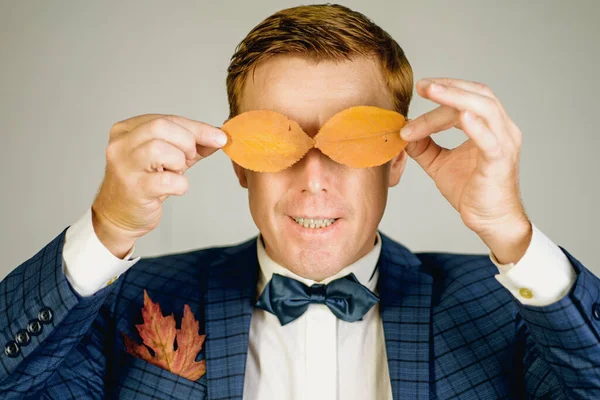 Divertido hombre pelirrojo anuncia sus productos. Banner para la publicidad de ropa de otoño. Modelo de pelo rojo está sosteniendo una hoja de otoño. Viernes negro y venta de negro. —  Fotos de Stock