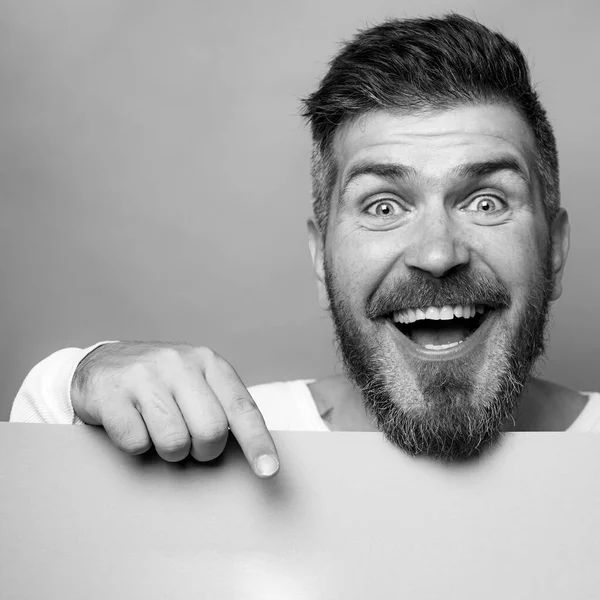 Een man met een baard die op een groen bureau wijst. Tradities en vieringen in maart. De groene kleur van de st. Patricks dag. Een gepassioneerd opgewonden mans gezicht. Kopieerruimte. — Stockfoto