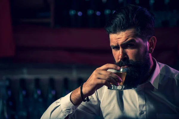 Przystojny brodaty mężczyzna pijący whisky w barze. Hipster pijący brandy w barze. Brutalny facet pijący alkohol. — Zdjęcie stockowe