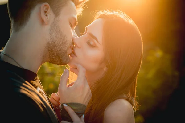 Verliebtes Paar küsst sich. Sexy Liebende küssen sich im Freien bei Sonnenuntergang. Sinnliche junge Menschen. — Stockfoto