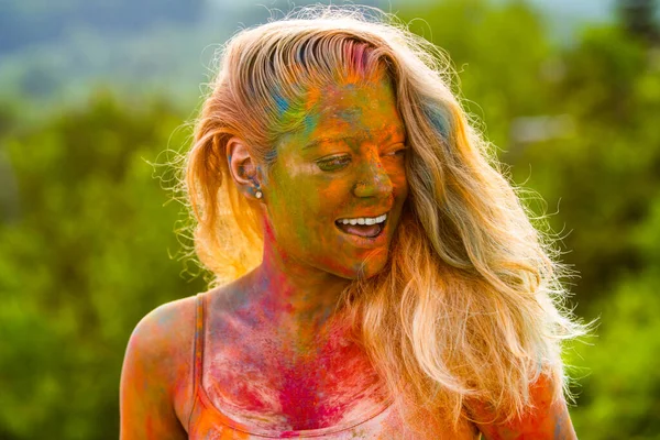 Joven alegre con pintura colorida en la cara y los cuerpos que se divierten en el festival holi. Mujer joven riendo con polvo de color en su piel. —  Fotos de Stock