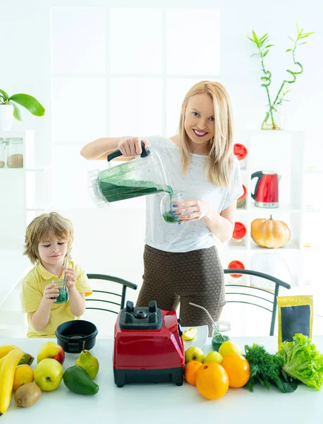 Mãe e filho misturando coquetel com frutas. O rapazinho bebe um batido suculento. Conceito de vida saudável, espaço de cópia. Smoothie saudável para crianças. — Fotografia de Stock