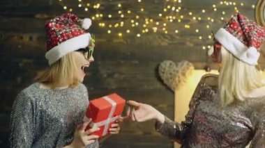 Yeni yıl hediyesi. İki güzel, modaya uygun, mutlu, gülümseyen, şenlikli Noel 'de poz veren ve komik suratlar yapan iki genç kız..