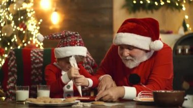 Noel Baba ve çocuk komik suratlar yapar ve yılbaşı kurabiyeleri pişirirler..