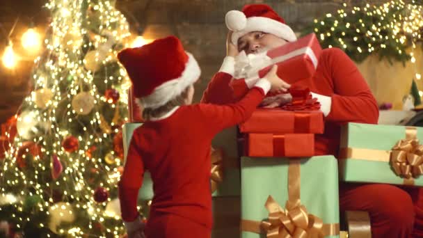 Santa Claus y el niño con cajas de regalo de Navidad en casa. Abuelo con niño preparar Navidad o Año Nuevo. — Vídeo de stock