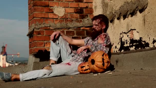 Halloween ünnep. Ijesztő véres zombi ember faragott sütőtökkel. — Stock videók
