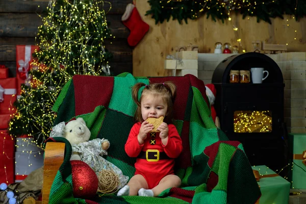 Retrato de linda menina em santa chapéu comer biscoitos de Natal. — Fotografia de Stock