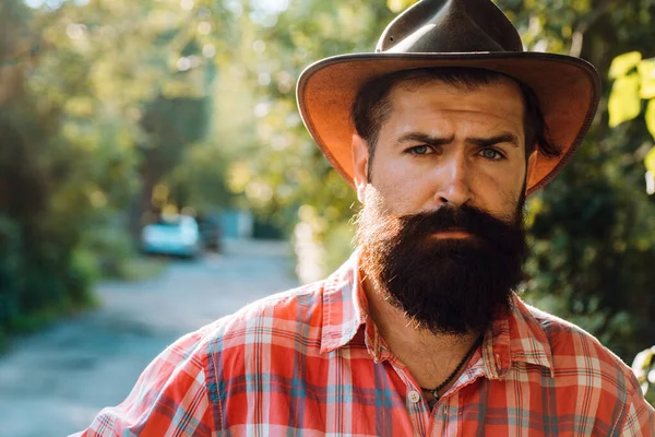Giovane bell'uomo in cappello da cowboy con lunga barba, baffi e acconciatura alla moda. — Foto Stock