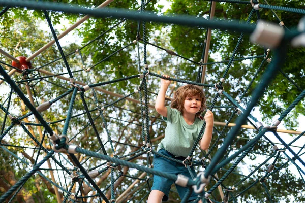 Insurance kids. Little kid boy climbing on the rope at playground. Health care insurance concept for family and children medical healthcare protection. — Stock Photo, Image