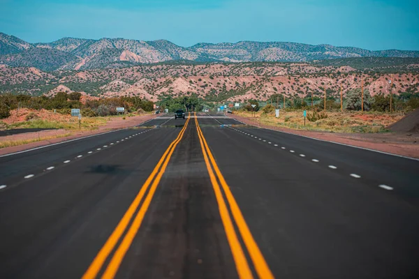 Panoramablick auf eine endlos gerade Straße, die durch die karge Landschaft des amerikanischen Südwestens führt. — Stockfoto