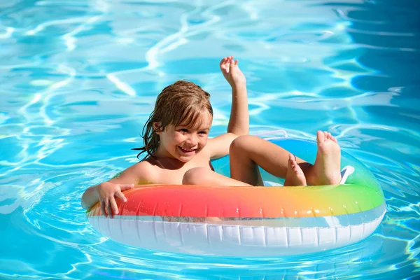 Kinderen in het zwembad. Zomer buiten. Happy kid spelen met kleurrijke zwemring in het zwembad. Kinderwaterspeelgoed. Kinderen spelen in een tropisch resort. Familie strandvakantie. — Stockfoto