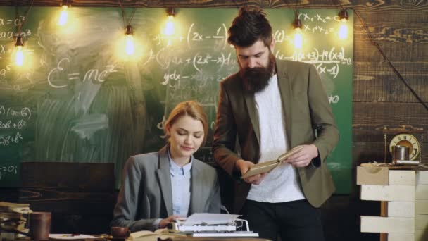 Professeur et secrétaire ou assistant travaillant à son bureau avec une machine à écrire vintage devant un tableau. — Video