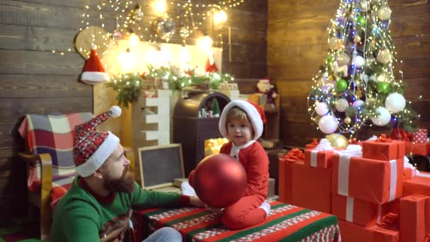Отец и сын украшают елку. Папа и ребенок держат рождественскую безделушку дома. Мальчик с родителями наслаждается Новым годом. — стоковое видео