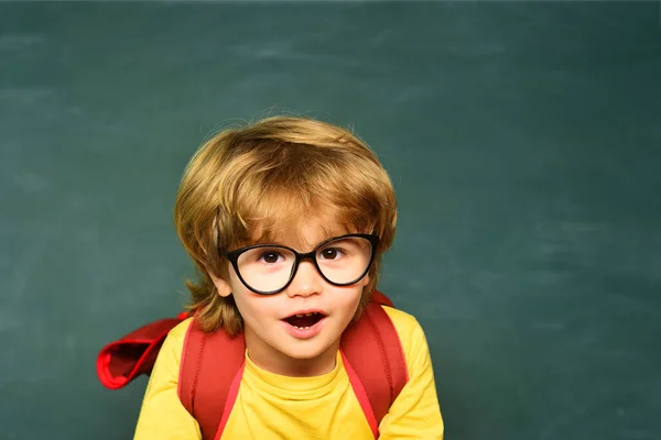 Utbildning. Ungarna gör sig redo för skolan. Lärandekoncept. Första skoldagen. Glada leende elever som ritar vid skrivbordet. Skolbarn mot grön tavlan. — Stockfoto