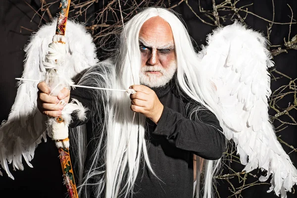 Bearded Man with angel wings. Senior man posing with angel wings. Tree spirit and fantasy concept. Ancient alchemy. Vampire man with white eyes.