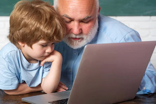 Dědeček s vnukem se učí lekci společně. Vzdělávání a učení lidé koncept - malý student chlapec a učitel pomocí notebooku. — Stock fotografie