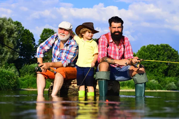 Nipote con padre e nonno che pescano in riva al lago. Padre, figlio e nonno in battuta di pesca. Un legame familiare. Pescatori. Buon pescatore con canna da pesca. — Foto Stock