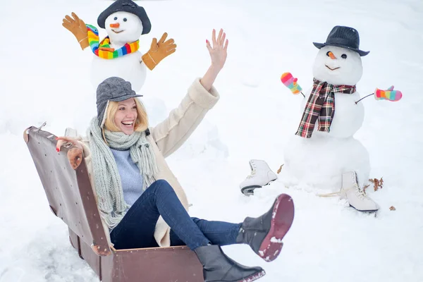 Happy smiling snow man and winter girl on sunny winter day. Winter holiday. Woman with suitcase. — Stock Photo, Image