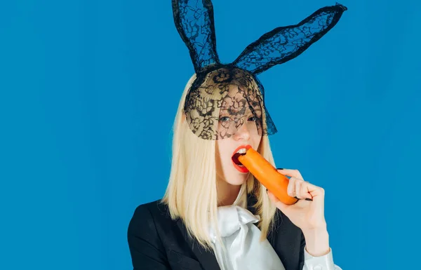 Милая женщина-кролик. Счастливая молодая женщина с заячьими ушами и пасхальными яйцами. Кролик ест морковку.. — стоковое фото