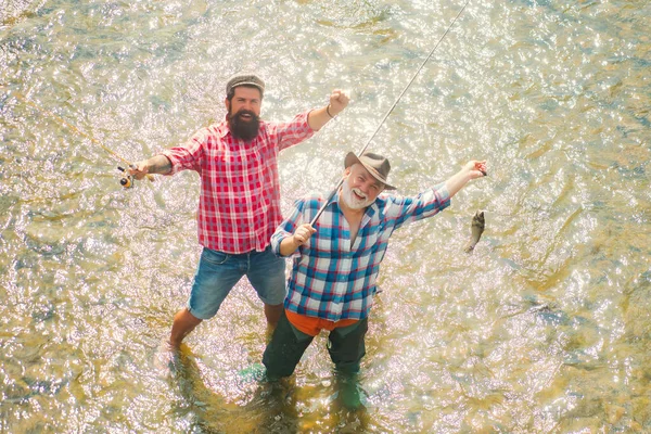 Uomini che pescano nel fiume durante la giornata estiva. Famiglia e generazione - vacanze estive e concetto di persone. Uomo pesca e relax mentre godendo hobby. — Foto Stock