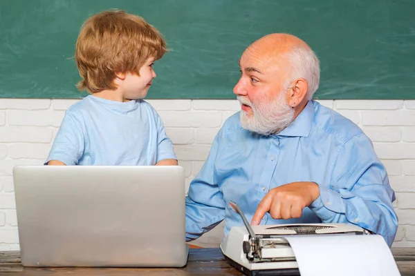 Portrait of confident old male teacher. Teacher helping his teen pupil on education class. Young boy doing his school homework with his father.