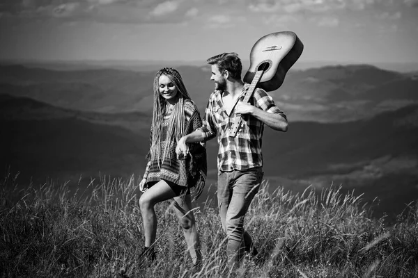 Γλυκιά αρμονία στα βουνά. Ευτυχισμένο ζευγάρι ταξιδιωτών έχουν μια βόλτα, χαμόγελο και να παίξει κιθάρα. — Φωτογραφία Αρχείου