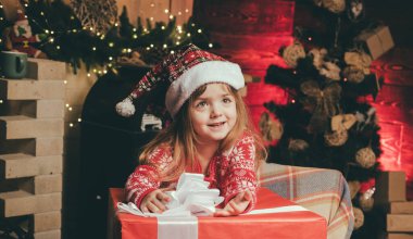 Büyük bir Noel hediyesi olan küçük mutlu noel kızı. Neşeli şirin çocuk Noel hediyesini açıyor. Mutlu çocuk Noel hediyesiyle.