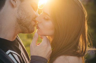 Sevgili çift gün batımında dışarıda öpüşüyor, aşk ve yaşam tarzı. Şehvetli bir öpücük. Genç çift öpücüğü, seksi aşıklar..