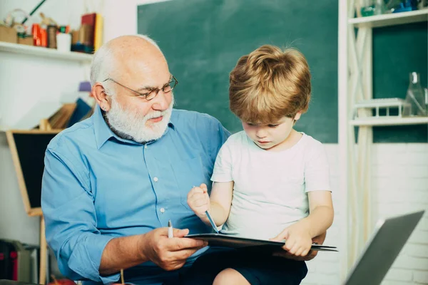 Leraar en leerling leren samen op school. Leuke kleine kleuter jongen met opa in een klaslokaal. — Stockfoto