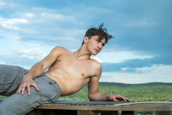 Muscular guy with sexy torso. Fashion portrait of young hot naked guy outdoor.