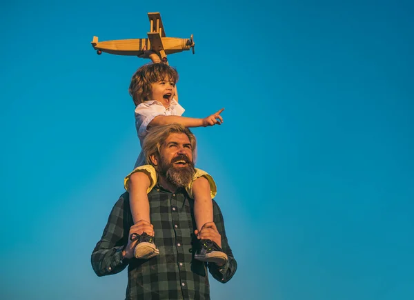 Chłopiec z zabawkowym samolotem siedzącym na ramionach ojców. Dzieci i tata bawią się. Kid pilot lotnik i tata marzy o podróży. — Zdjęcie stockowe