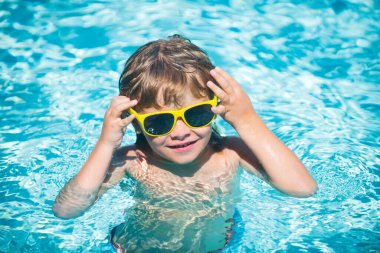 Yaz tatilinde plajda oynayan bir çocuk. Doğada deniz, kum ve mavi gökyüzü olan bir çocuk. Mutlu çocuklar deniz kenarında tatildeler, suda koşuyorlar..