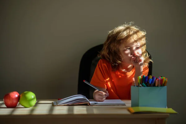 Der kleine Schuljunge macht zu Hause Hausaufgaben. Kind denkt, Kinder träumen. — Stockfoto