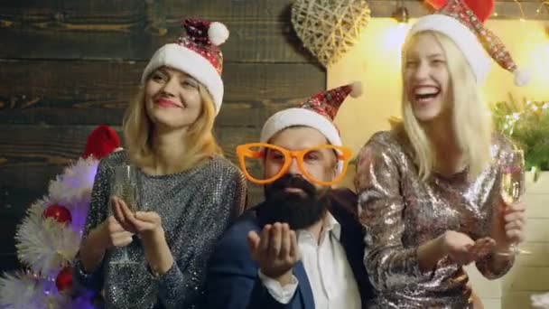 Neujahrskonzept Weihnachten. Styling Santa Hipster mit langem Bart und Freundinnen posieren auf dem hölzernen Weihnachtshintergrund. — Stockvideo