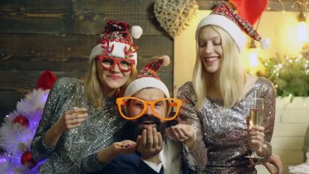 Šťastní přátelé, kteří mají Vánoce doma, pijí víno a cinkají sklenicemi. Vtipní lidé v červeném Santově klobouku. Skupina mladých přátel baví na silvestrovské párty. — Stock video