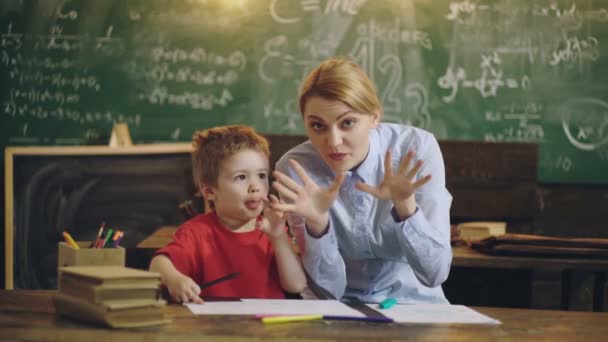 Grundskolelärare. Mor hjälper grabben i klassrummet. — Stockvideo