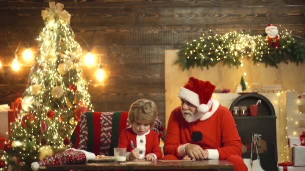 Avô e criança na árvore de Natal. Criança feliz escrever carta de desejo em casa. Lista de desejos para o Pai Natal. Rapaz sonhador na véspera de Natal. Acredite no milagre do Natal. Família férias tradição. — Vídeo de Stock