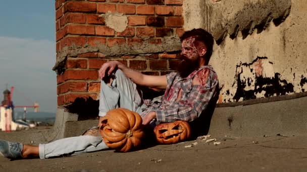 En cámara lenta. Terrible hombre zombi sangriento con calabaza tallada. Horror. Concepto Halloween. — Vídeo de stock