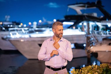 Yatın yanındaki zengin adam. Zengin milyoner adam lüks yaşam tarzının tadını çıkarıyor. Özel bir yatta milyoner bir adam. Finansal özgürlük. Zengin bir adamla pahalı bir yat. VIP premium lüks elit konsept