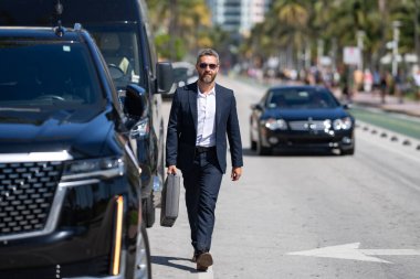 İspanyol işadamı dışarıda. Lüks bir arabanın yanında duran zengin bir işadamı. Küresel. Başarılı bir iş. Zarif bir iş adamı pahalı bir arabanın önünde duruyor. Başarılı iş adamı