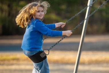 Sarışın çocuk dışarıda sallanıyor. Salıncakta gülen çocuk. Oyun bahçesinde oynayan sevimli çocuk. Heyecanlı çocuk salıncakta sallanıyor. Yaz parkındaki sevimli çocuk. Parkta sallanan oyuncu çocuk. Mutlu çocukluk