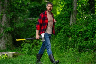 Ormanda baltası olan çalışkan bir adam. Büyük baltası olan sakallı bir oduncu. Ekose gömlekli vahşi sakallı bir adamın portresi bir balta tutuyor. Erkek güzelliği ve erkeklik