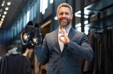 Moda mağazasındaki müşteri farklı ayakkabı stillerini değerlendirir. İş adamı kendine güvenerek şık ayakkabıları bir ayakkabı mağazasında seçer. Resmi görünmek için klasik deri ayakkabılar. Resmi ayakkabılar. Deri ayakkabılar.