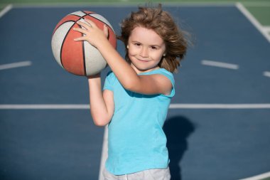 Dışarıda basketbol oynayan bir çocuk. Mutlu çocuk basketbol topunu tutuyor. Çocuklar için yaz sporu. Basketbol maçındaki çocuk. Çocuk parkında antrenman yapıyor. Çocuklar için sağlıklı açık hava aktivitesi