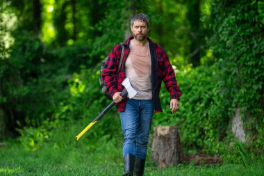 Kareli gömlekli yakışıklı ya da oduncu balta tutuyor. Oduncu ya da oduncu. Erkeklik kavramı. Vahşi, güçlü, çekici bir adam ormanda baltayla odun kesiyor. Ormanda baltası olan oduncu.