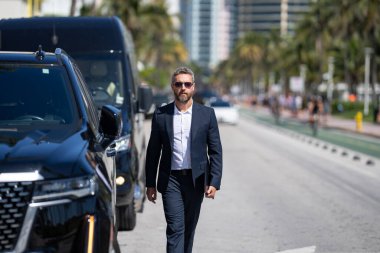 Olgun bir iş adamı. Lüks bir arabanın yanında duran zengin bir işadamı. Küresel. Başarılı bir iş. Zarif bir iş adamı pahalı bir arabanın önünde duruyor. Başarılı iş adamı