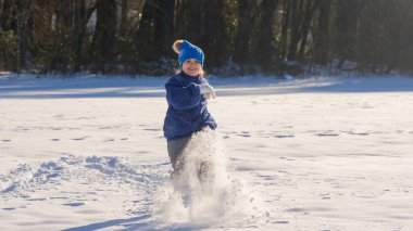 Karlı kış parkındaki çocuk. Kış çocuğu kar taneleriyle oynar. Çocuklar kış tatili. Kışın çocukluk anıları. Kışın bir çocuğun portresi. Noel tatilinde dondurulmuş eğlence