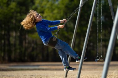 Heyecanlı çocuk eğleniyor. Çocuk bahçesinde mutlu bir çocuk. Havada sallanan kaygısız çocuk. Mutlu çocuklar dışarıda oynuyor. Sarışın çocuk heyecandan titriyor. Dışarıdaki oyuncu çocuk. Komik çocuk suratı