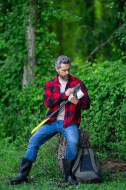 Ekose gömlekli oduncu doğa kökenli. Acımasız oduncu. Odun kesiyorum. Keskin bıçak. Vahşilik ve erkeklik. Sakallı oduncu. Oduncu tarzı. Baltalı adam. Sakallı adam, balta tut.